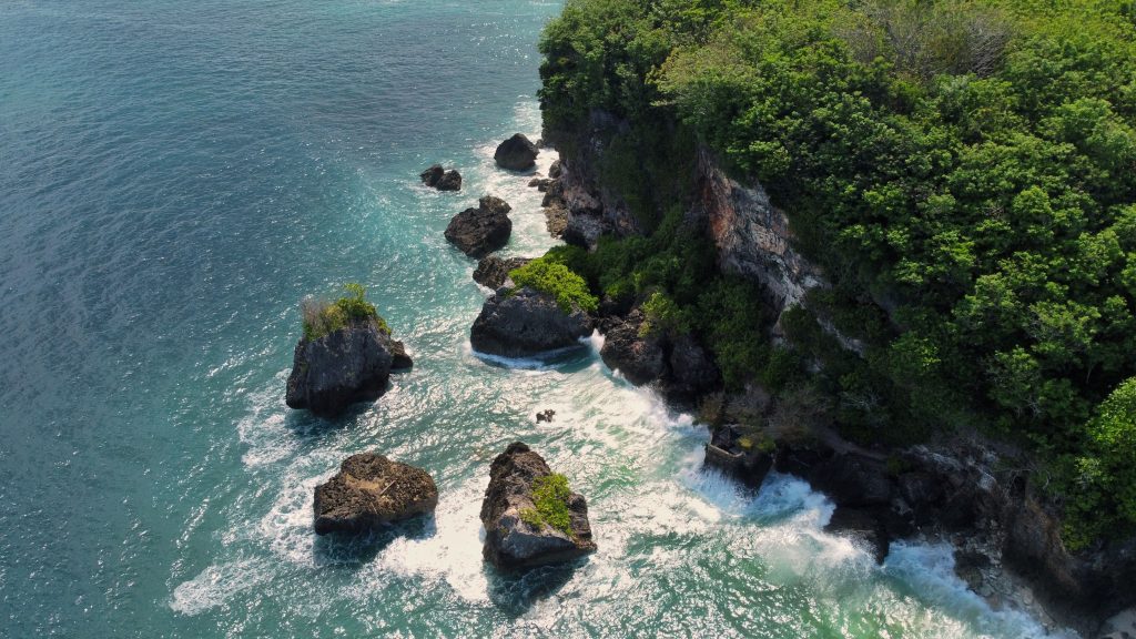 Stunning aerial view of a rocky coastline with lush greenery in Bali, Indonesia.travel with right-style.com